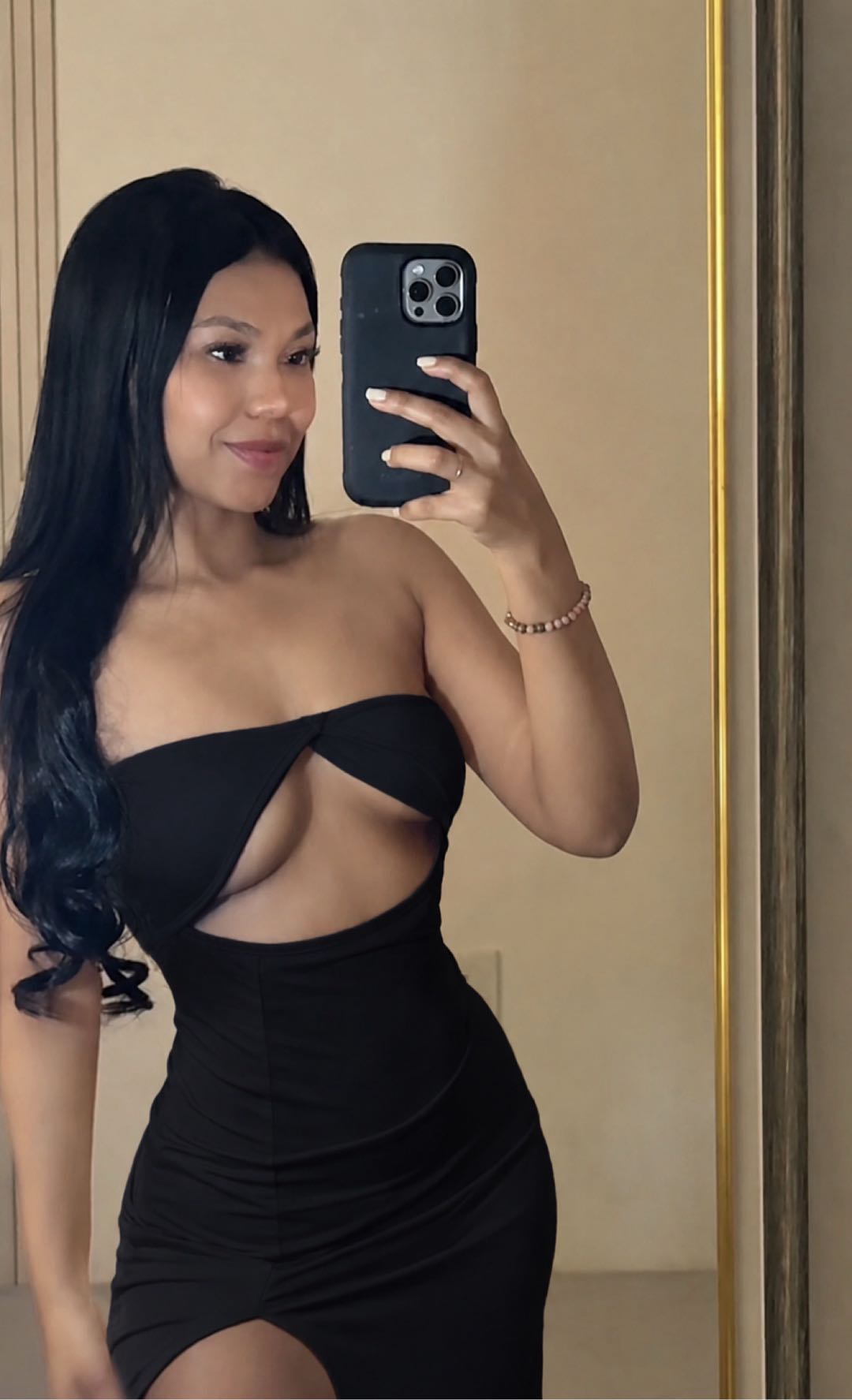 Woman in a black cut-out dress taking a mirror selfie