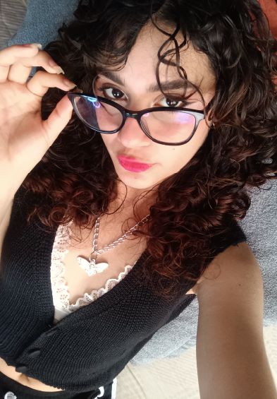 Woman with curly hair and glasses taking a selfie