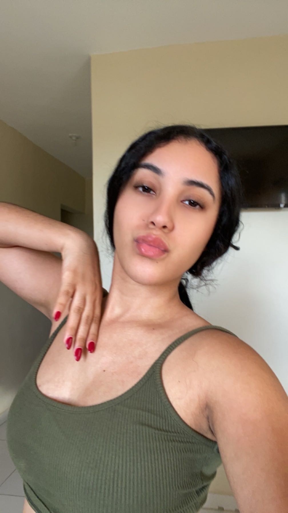 Woman in an olive green top taking a selfie at home
