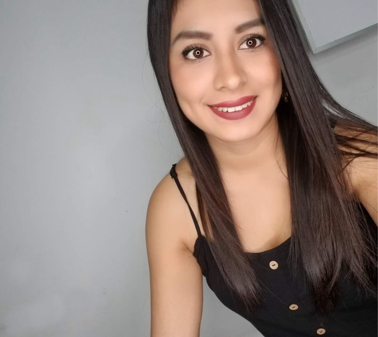 Woman with long dark hair smiling in a black top
