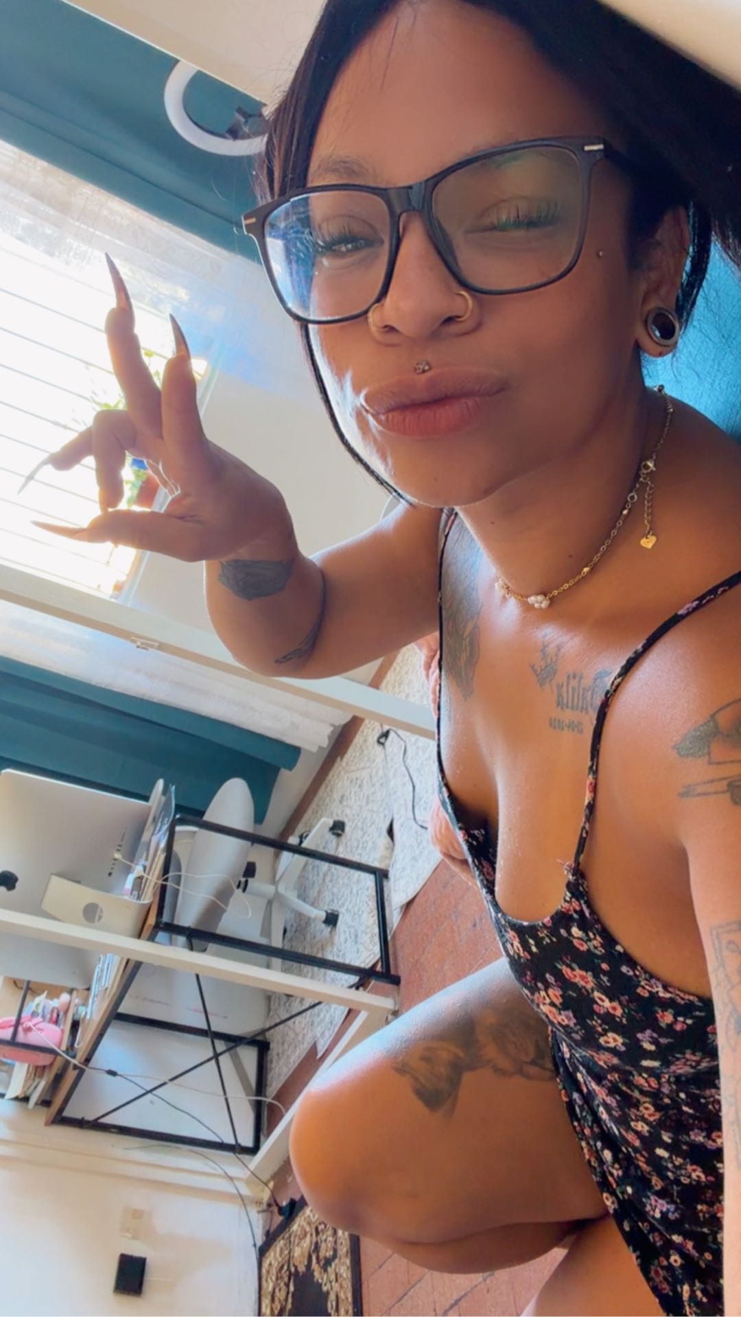 Woman with glasses in a floral bodysuit taking a selfie